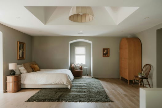 A neutral bedroom with a large bed and wooden wardrobe.